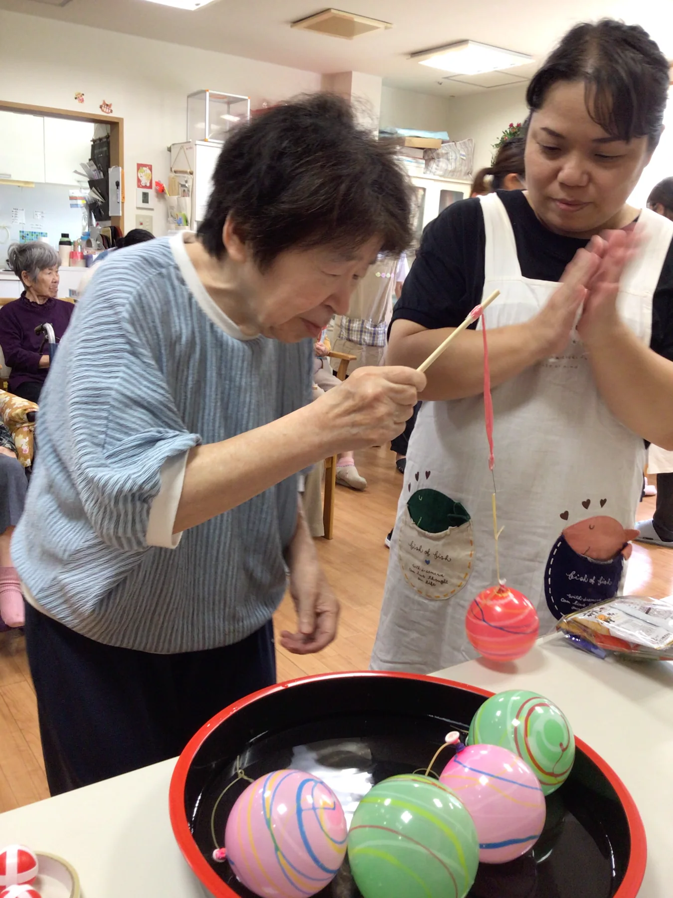 夏祭りのゲームを入居者と職員が一緒に楽しむ様子