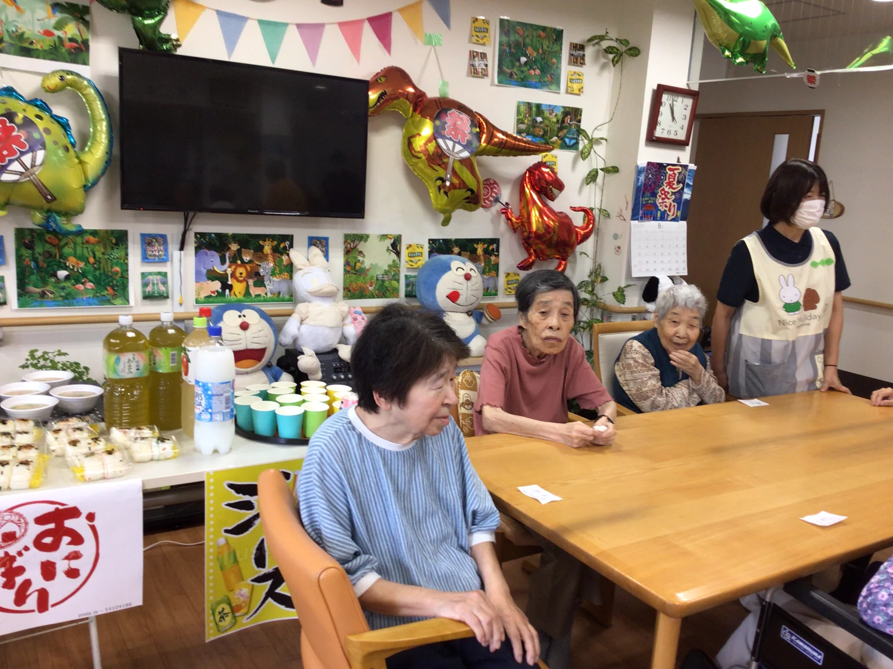 夏祭りの飾り付けをした室内で過ごす入居者と職員