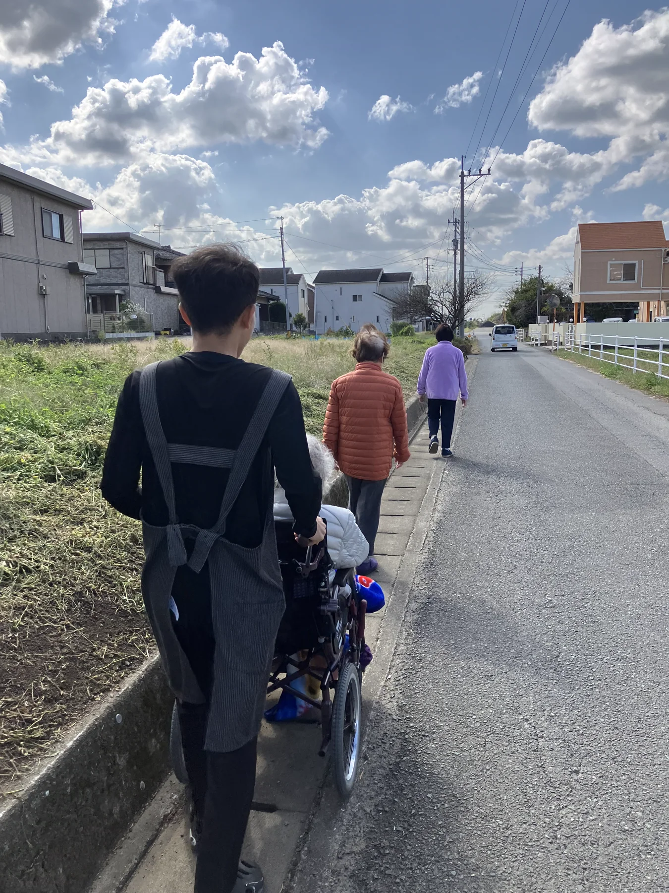 職員と入居者が近隣を散歩する後ろ姿