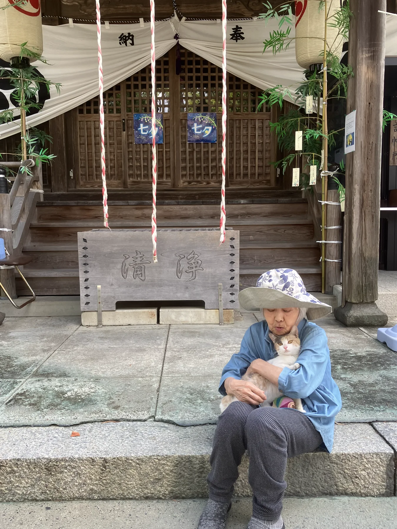 七夕飾りのある神社で猫を抱く入居者