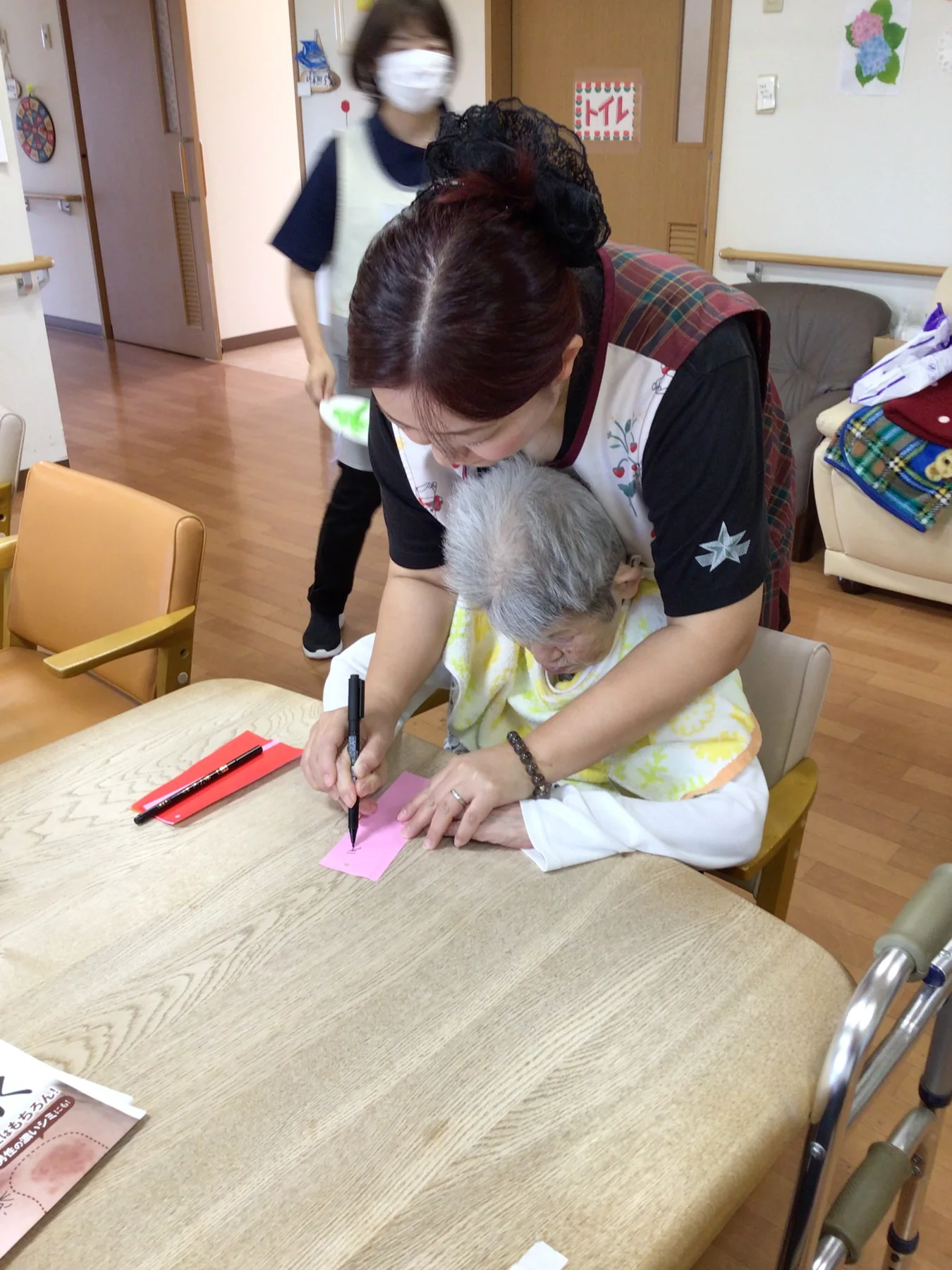 めぐみ苑の職員が入居者の書く活動をそばで支える様子