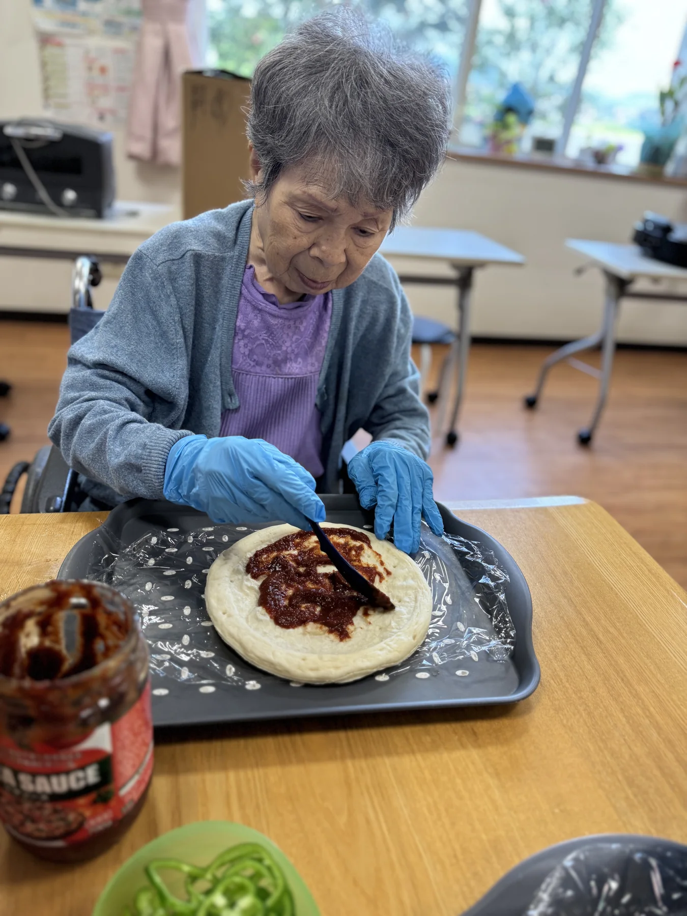 入居者がピザ生地にソースを塗る様子