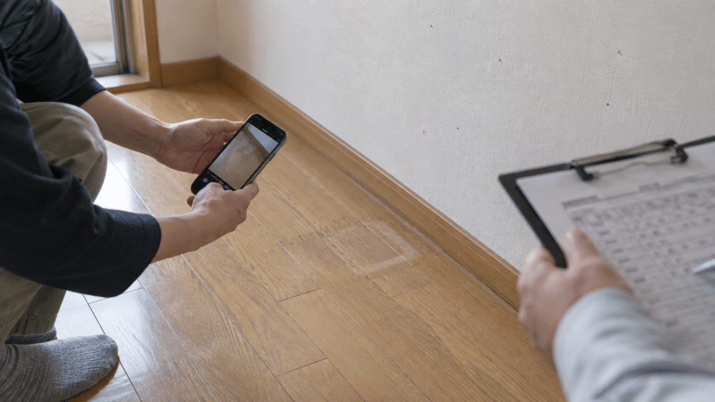 退去前の賃貸住宅で床の使用痕を写真に記録する手元