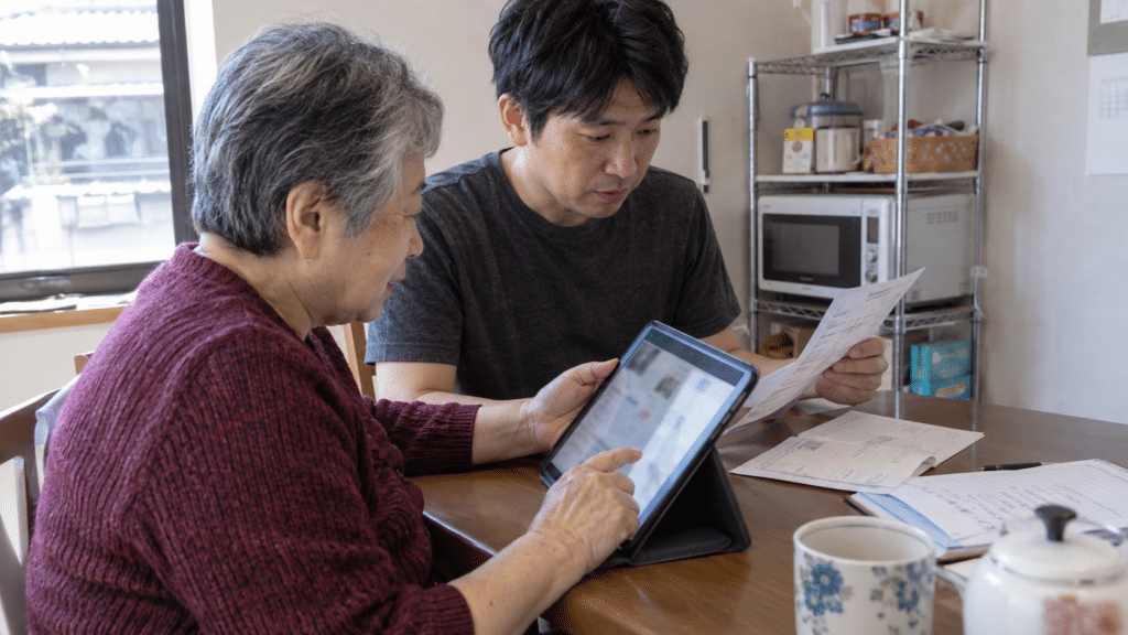 紙の資料とタブレットを一緒に確認する母親と息子
