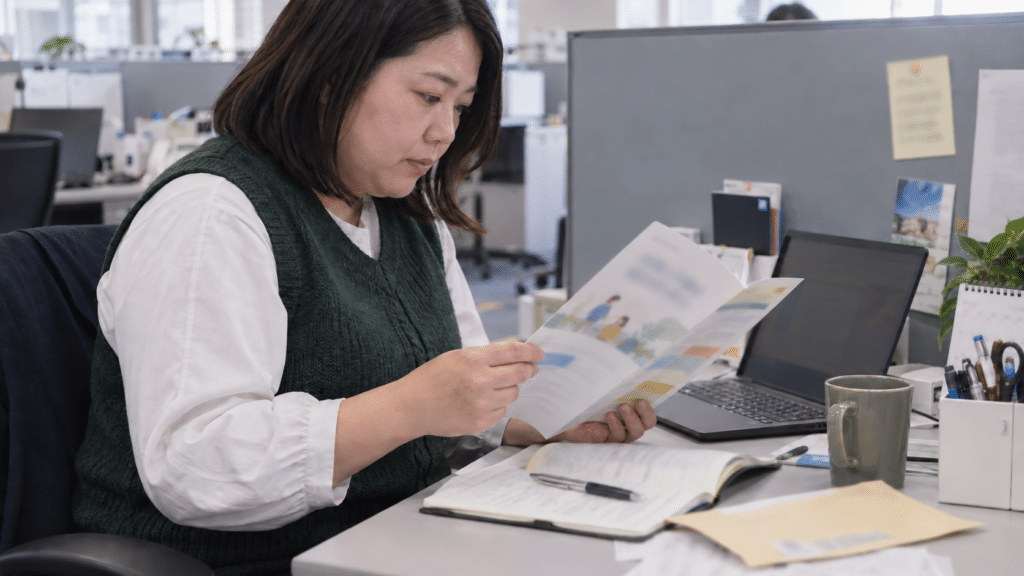 職場の机で会社からの介護制度の案内を読む従業員
