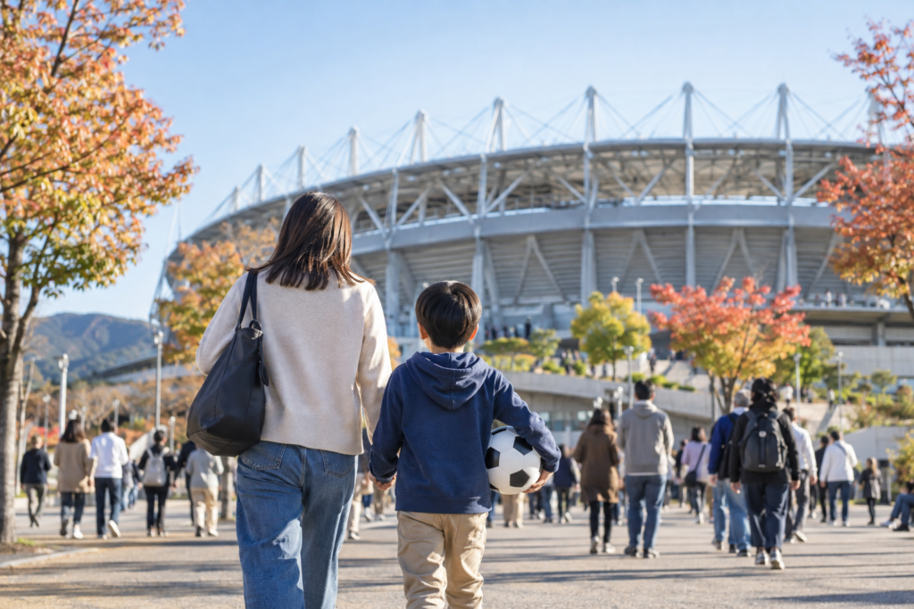 サッカーボールを手にスタジアムへ向かう親子の後ろ姿