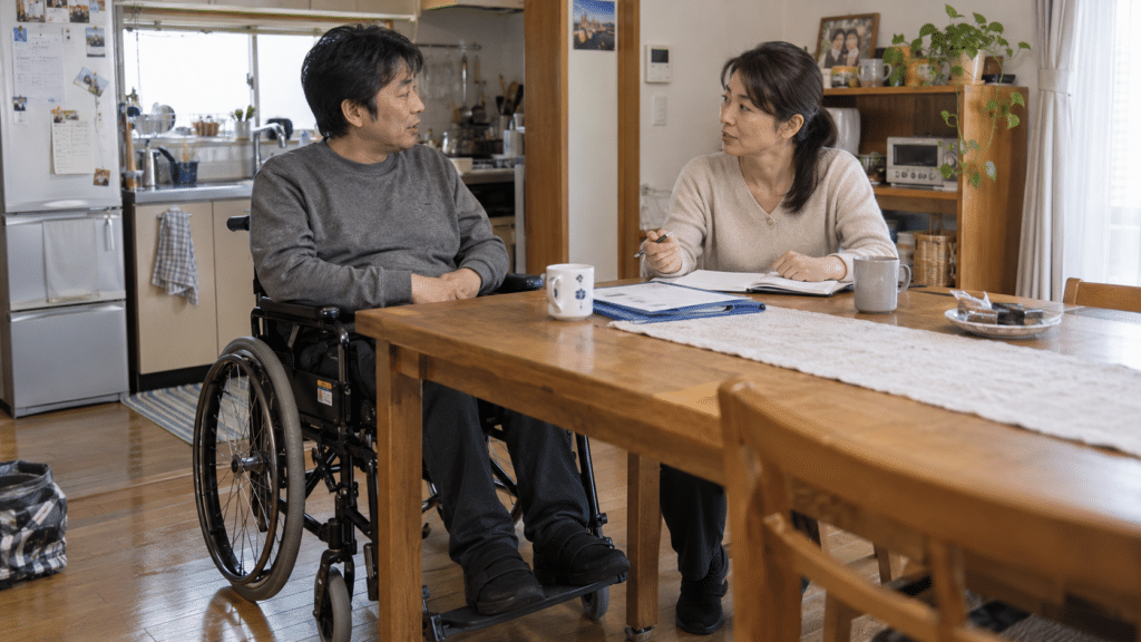 車いすを使う本人と家族が自宅で生活と介護の状況を話し合うイメージ